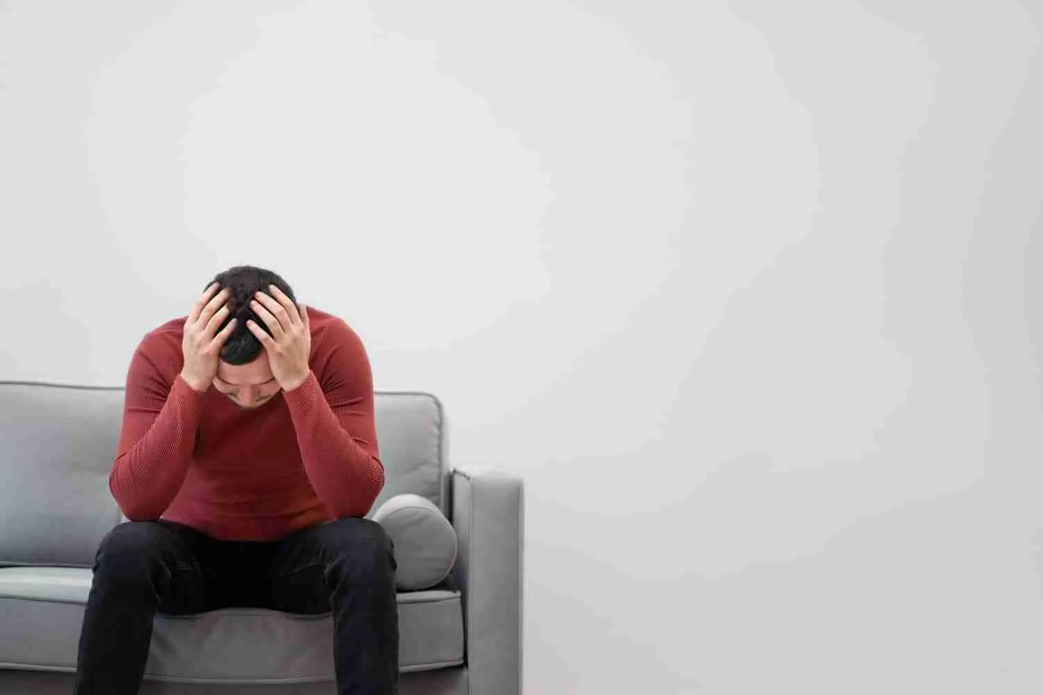 Man experiencing distress and holding his head while sitting on a sofa, illustrating the struggle with Anxiety Disorders. Man experiencing distress and holding his head while sitting on a sofa, illustrating the struggle with Anxiety Disorders.